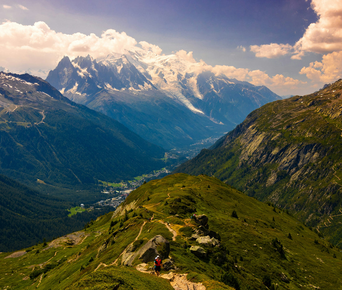 Hikers on a green alpine trail below snowy peaks, Mont Blanc region