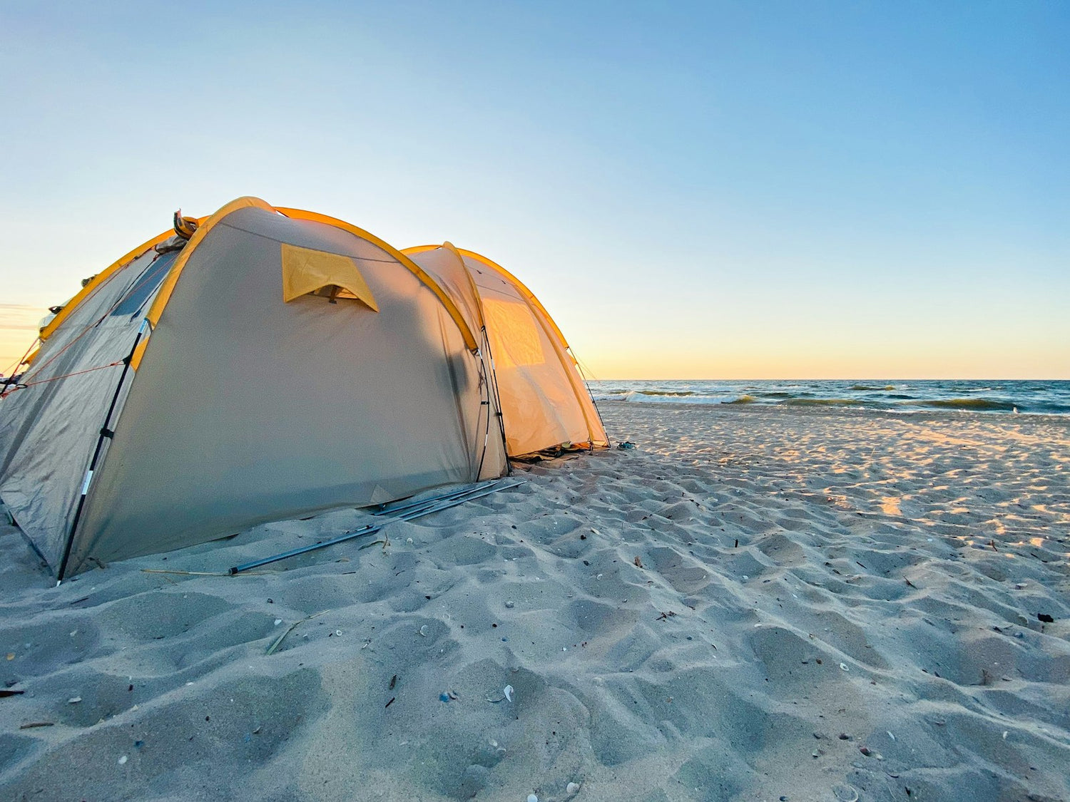 White shade tent set up on a sandy beach on a bright summer day