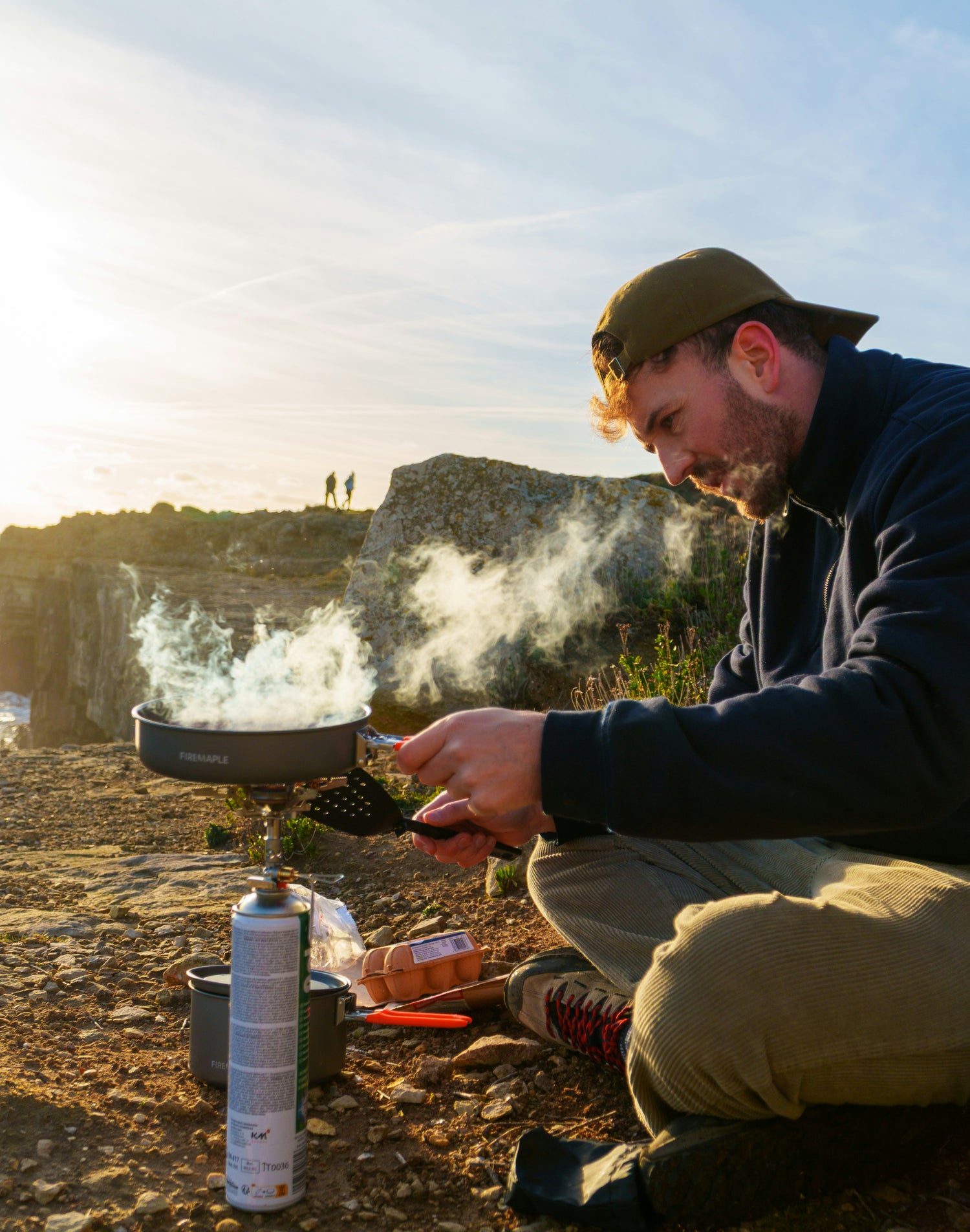 Camp cooking setup with a portable stove and cookware outdoors