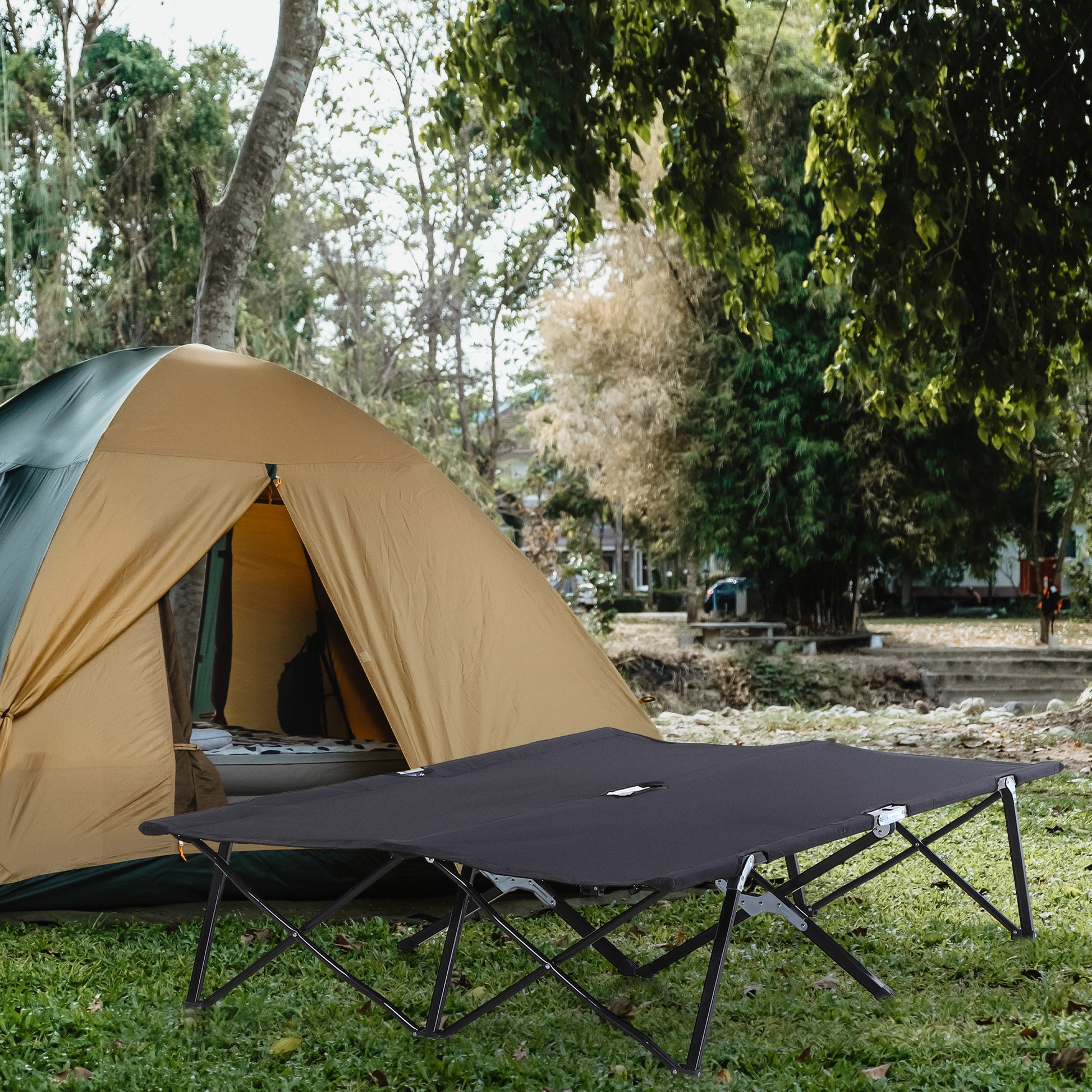Extra-wide camping cot set up beside a tent with its carry bag