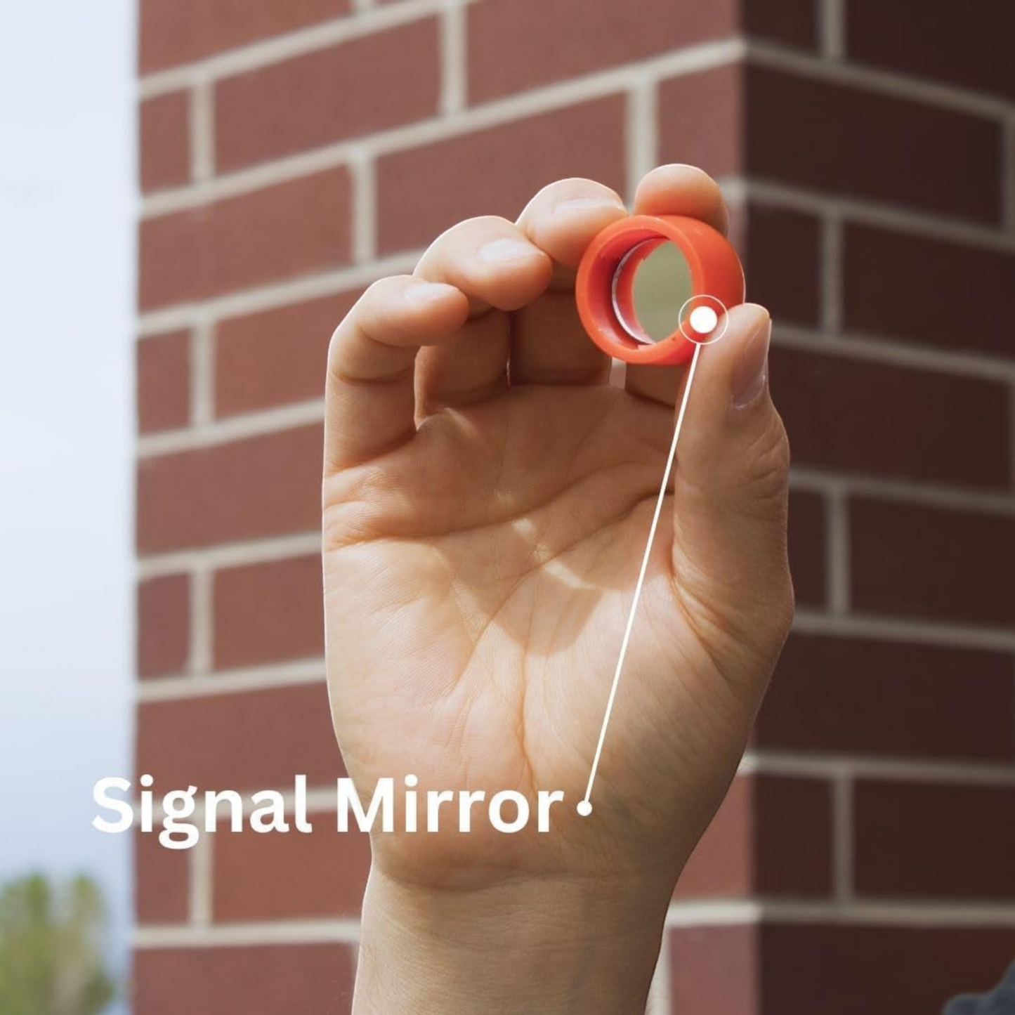 CAMPONGO™ 5-in-1 survival tool showing the integrated signal mirror held between fingers against a brick wall background
